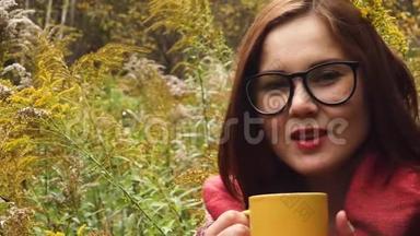 年轻女子从杯子里喝热茶以保暖